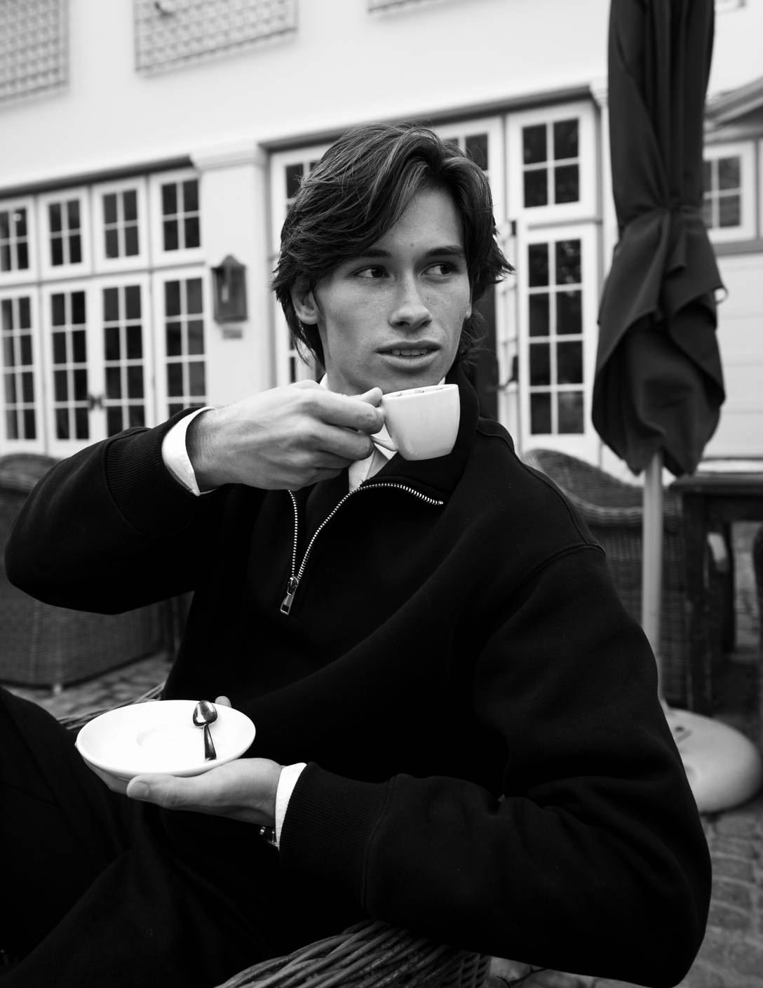 Ethan McCormick seated outdoors with an espresso, looking off frame